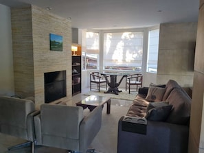 Una sala de estar con chimenea, un sofá, una mesa de centro y un comedor con sillas y una mesa.
