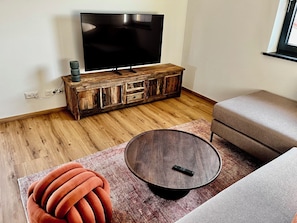 A living room with a television on a wooden cabinet, a round coffee table, a red sofa, and a patterned rug.