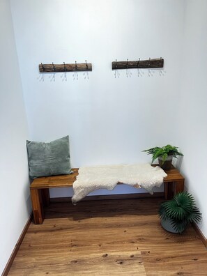 Eine Sitzecke mit einer Bank, einem Kissen, einer Pflanze und einem an der Wand befestigten Haken.