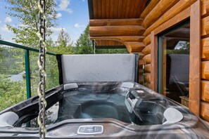 Ein Whirlpool mit Bedienfeld, umgeben von Holzwandverkleidung und einer Glasreling.
