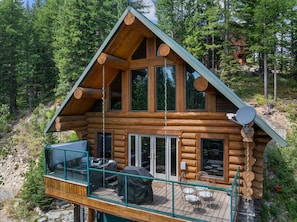 Eine Blockhütte mit einer Veranda, Sitzgelegenheiten im Freien und einer Satellitenschüssel.