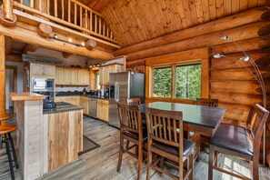 L’intérieur d’un chalet en bois comprend une cuisine, un coin repas et une grande fenêtre.