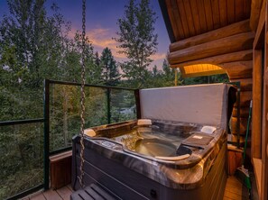 Un bain à remous sur un balcon, avec vue sur les arbres et le coucher du soleil.
