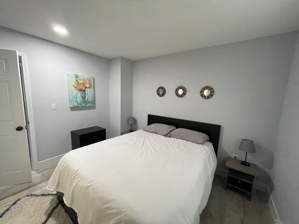 A bedroom with a bed, bedside tables, a nightstand, a lamp, and wall decorations.