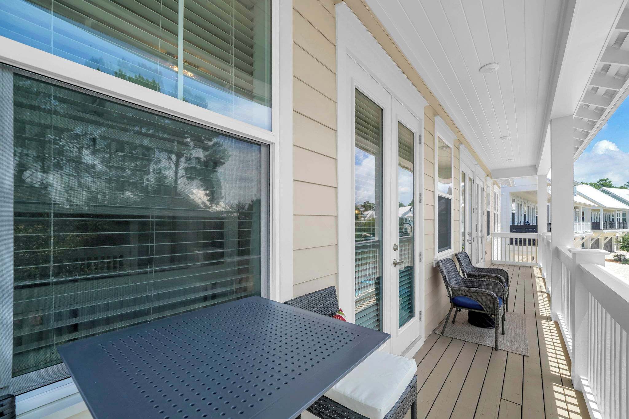 A covered outdoor area with a table and chairs, large windows, and a view of the surrounding area.