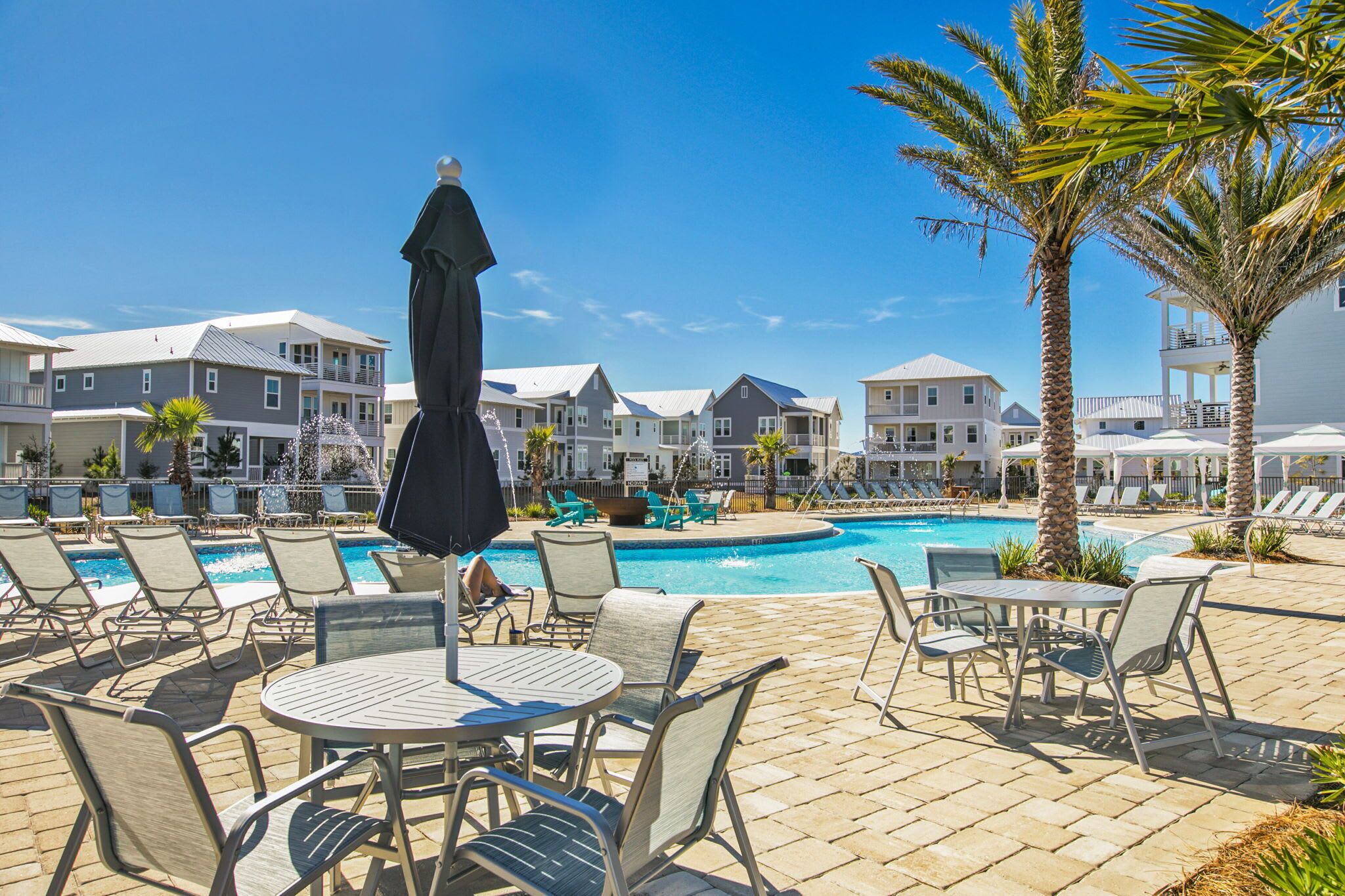A poolside area with lounge chairs, a table, and umbrellas.