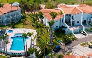 Ein Resort mit mehreren Gebäuden, einem Pool und Palmen.