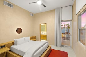 Une chambre d’hôtel avec un lit, une table de chevet, un élément de décoration circulaire fixé au mur, un ventilateur de plafond et une vue sur l’extérieur.