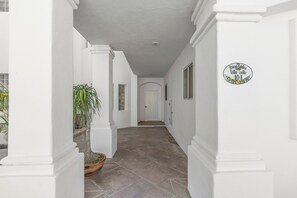 A hallway with white walls, a potted plant, and a door at the end. - New listing  - Stylish Palmilla 3-Bedroom Condo with Shared Pool (Palmilla)