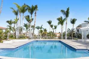 Ein Swimmingpool, umgeben von Palmen und einem weißen Gebäude.