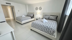 A hotel room with two beds, a desk, and a bathroom. - Wonderful Apt! 14 floor. Parking included! (Sunny Isles Beach)
