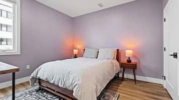 Una camera da letto con un letto, lampade sui comodini, una finestra e una porta.