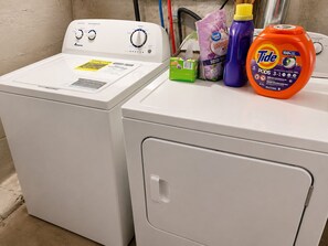 A front-loading washing machine with a control panel, a detergent bottle, and a fabric softener on top.