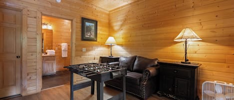 Una habitación acogedora con una mesa de futbolín, un sofá y un ventilador.