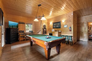 Ein Holzinterieur mit einem Billardtisch, einem Fernseher und einem Willkommensschild.