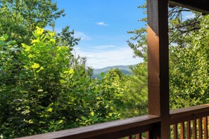A wooden deck overlooking a dense forest with a mountain range in the distance. - Secluded Mountain Cabin with Hot Tub, Fire Pit, Games and Views (Sevierville)