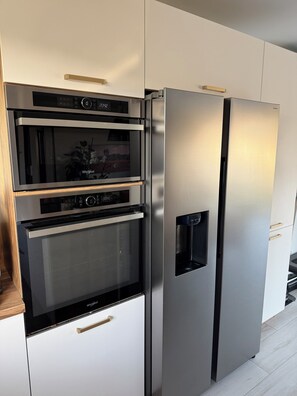 A stainless steel refrigerator with a water dispenser and a microwave above it. - Smart home, EV charging station, air-conditioned, near Cognac, sleeps 6 (Châteaubernard)