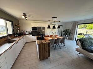 Une cuisine moderne avec un îlot central, un coin repas avec des chaises et un canapé.