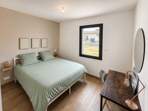 Une chambre à coucher avec un lit, des tables de chevet, un bureau et une fenêtre.