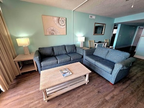 A living room with a sofa, a coffee table, and a painting on the wall. - Club Regency (Myrtle Beach)