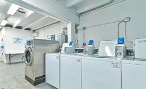 Ein Waschraum mit Industriereinigungsmaschinen und Trocknern, Bedienfeldern und einem Schild mit Anweisungen.