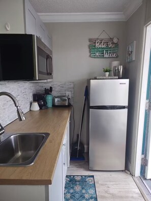 Eine kleine Küche mit einem Edelstahlkühlschrank, einer Mikrowelle und einem Toaster.