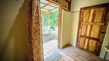 A wooden door leading to an outdoor area with a wheelbarrow and greenery visible.