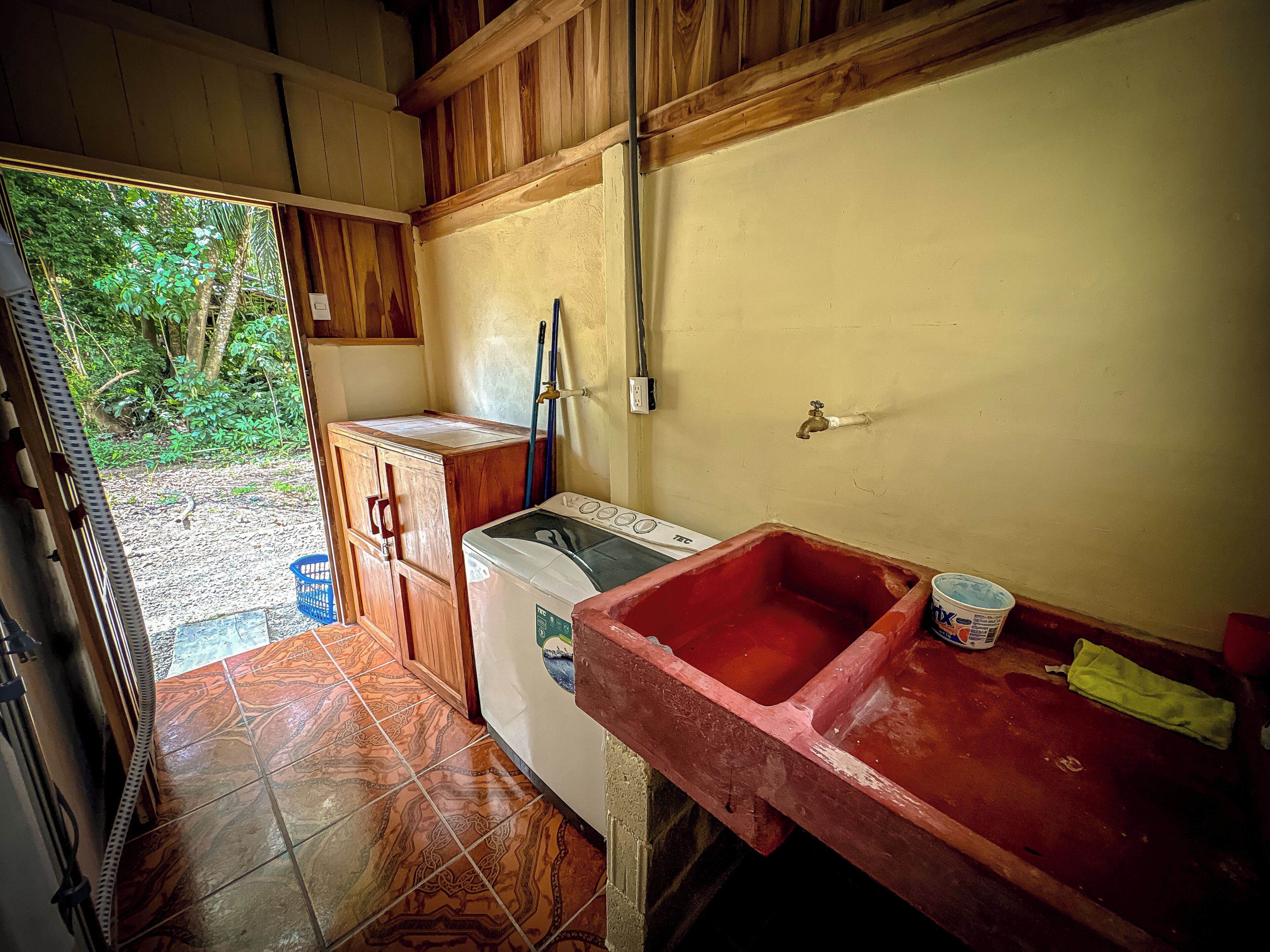 A compact kitchen with a washing machine, a sink, and a wooden cabinet.
