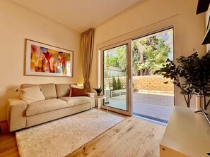 Uma sala de estar moderna com sofá, tapete, quadro e porta de vidro deslizante para área externa.