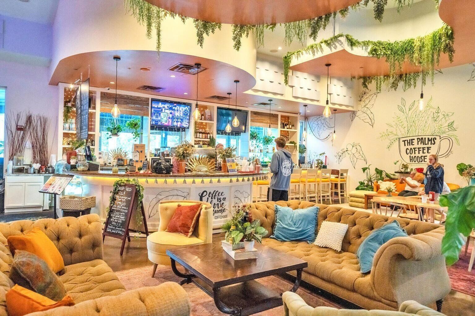 A cozy coffee shop interior with seating, a bar area, and decorative plants.