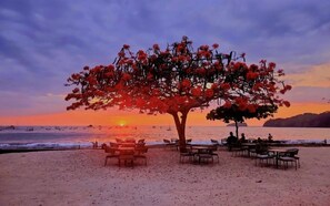 Un restaurant situé en bord de mer, avec une terrasse et une vue sur le coucher de soleil sur l’océan.
