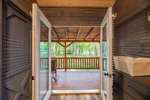 A wooden deck with a bench, a covered area with a roof, and a view of a forest. - Theater! Sauna! Jacuzzi! Firepit! EV Charger (Cosby)