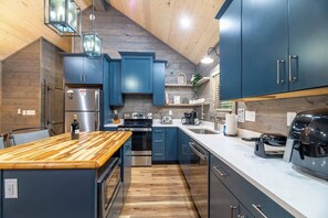 A modern kitchen with dark blue cabinets, stainless steel appliances, and a wooden island. - Theater! Sauna! Jacuzzi! Firepit! EV Charger (Cosby)