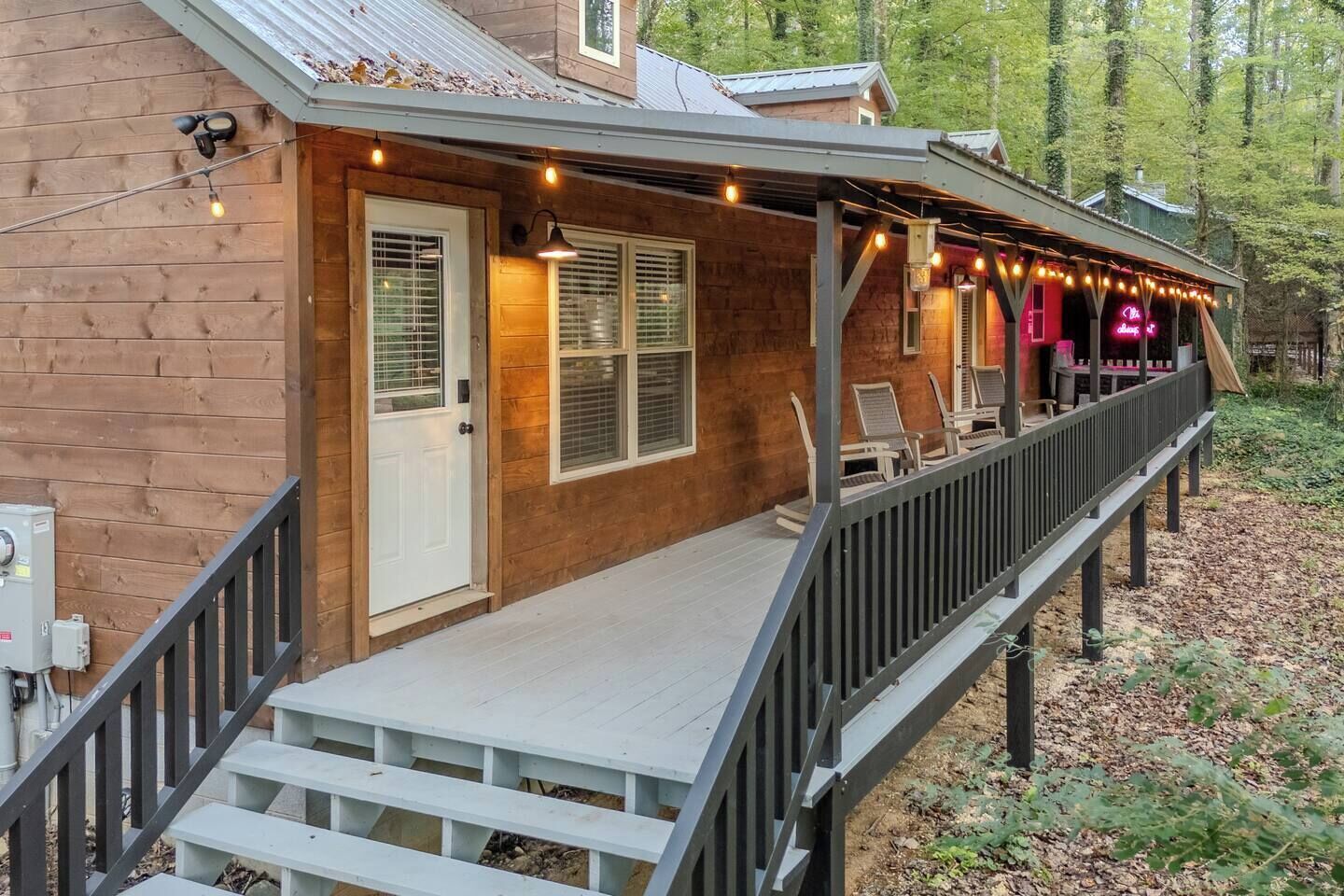 Eine Holzhütte mit Veranda, Sitzgelegenheiten im Freien und Lichterketten.