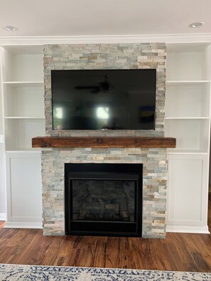 A fireplace with a stone surround and a flat-screen TV mounted above it. - Wonderful 4-bedroom house with AC in sunny San Diego (San Diego)
