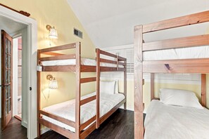 A bunk bed room with a wooden frame, a wall-mounted light, and a door with frosted glass panels. - Sand Dollar W-210 (Pensacola Beach)