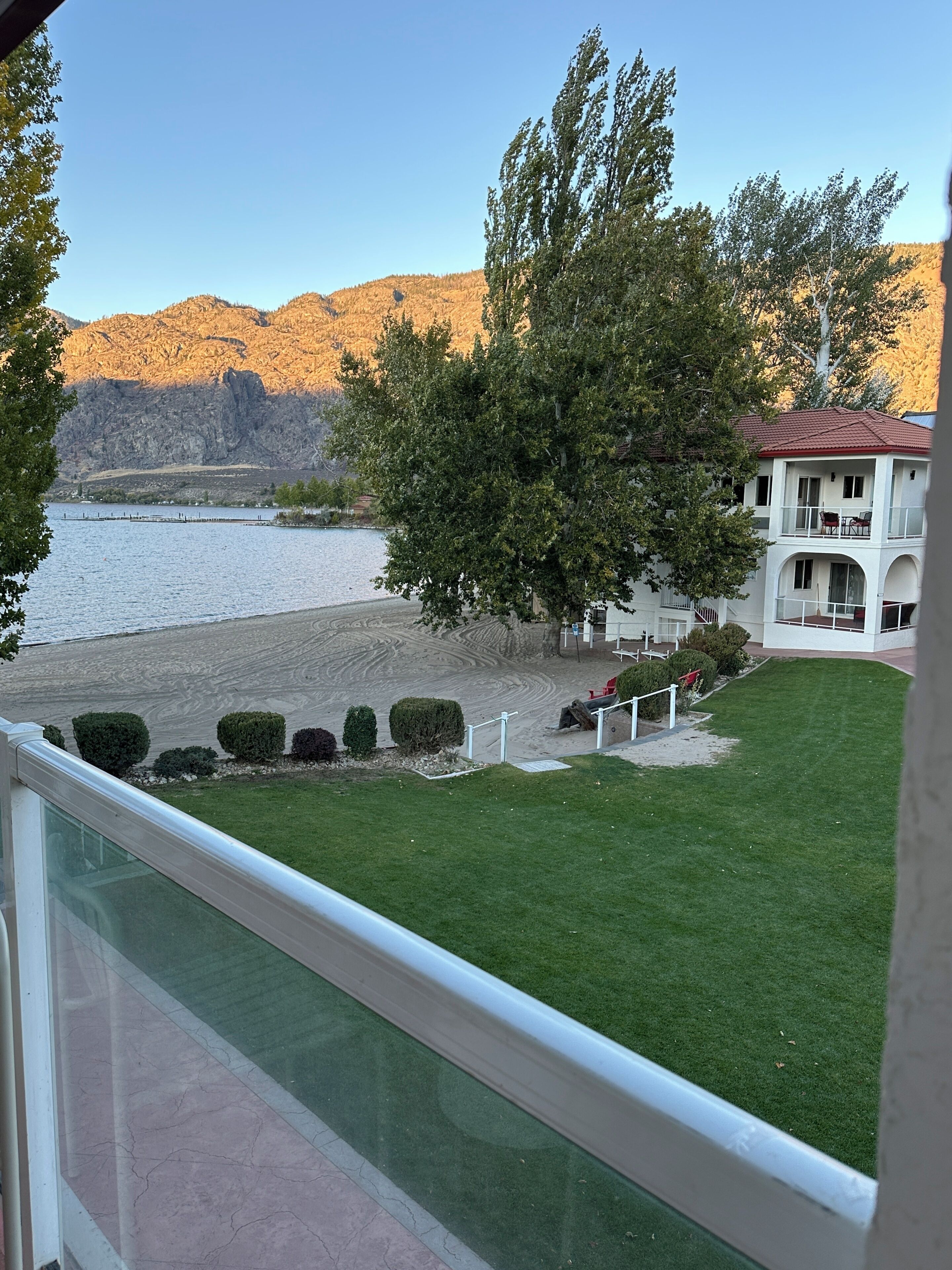 A view of a grassy area with a building and a body of water in the background.