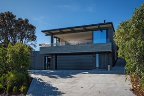 A modern two-story house with a garage, large windows, and a flat roof. - Black House Red Roof - Langs Beach Holiday Home (Langs Beach)