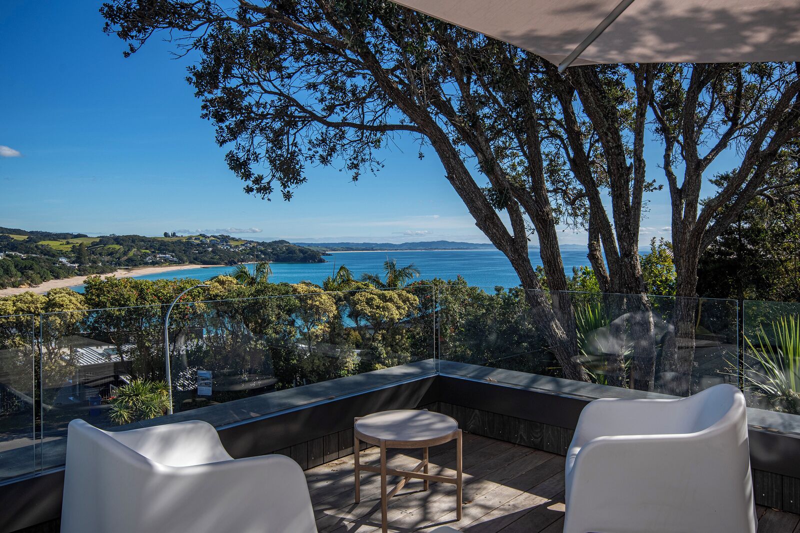 Een balkon met uitzicht op zee, een tafel en twee stoelen.