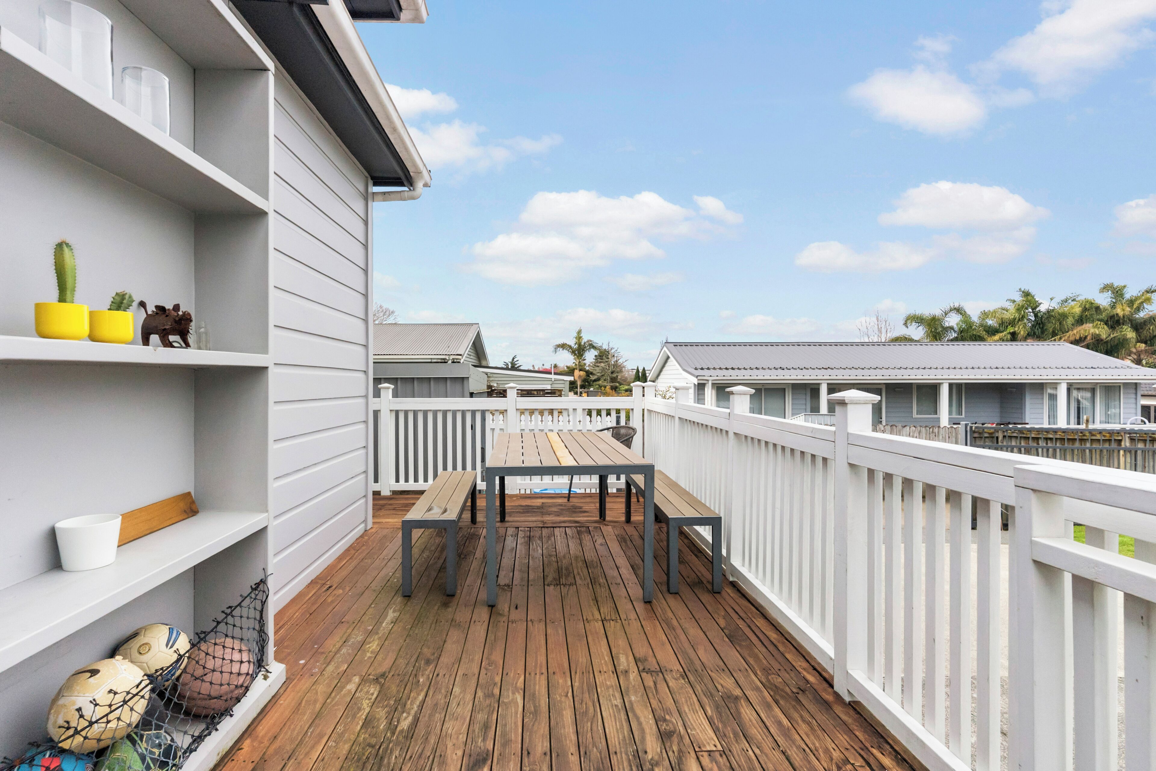 A wooden deck with a white railing, a table, and chairs.