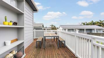 A wooden deck with a white railing, a table, and chairs.