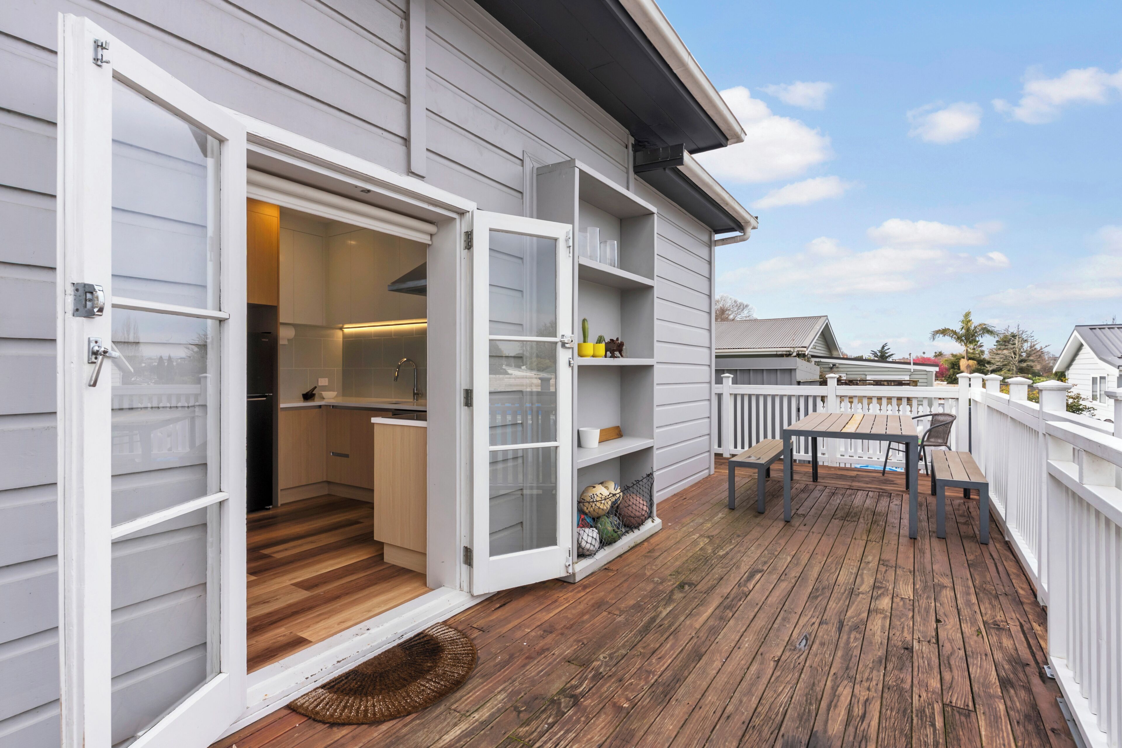 A deck with a wooden floor, a table, and chairs.