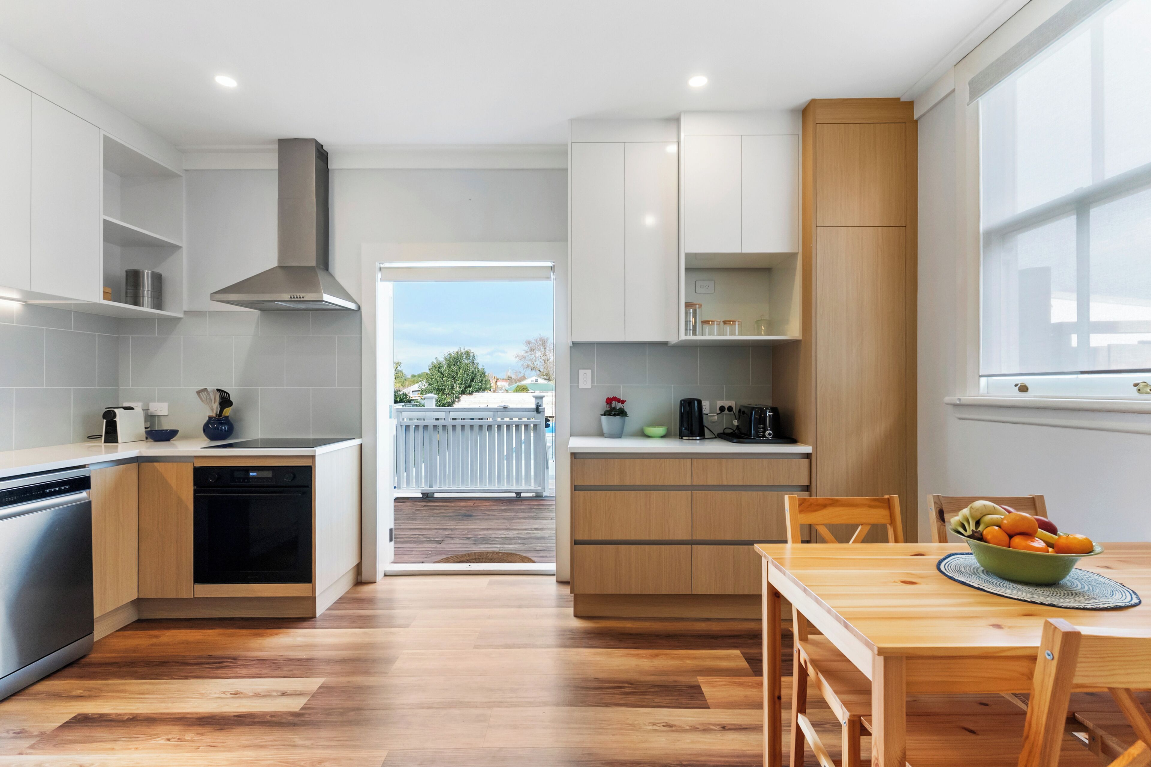 A modern kitchen with a central island, built-in appliances, and a view to the outside.