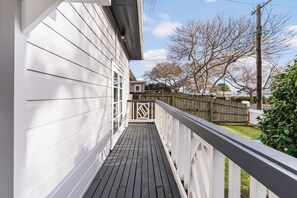 A wooden deck with a white railing, leading to a house with a white exterior. - Poolside Pause - Auckland Holiday Home (Auckland)