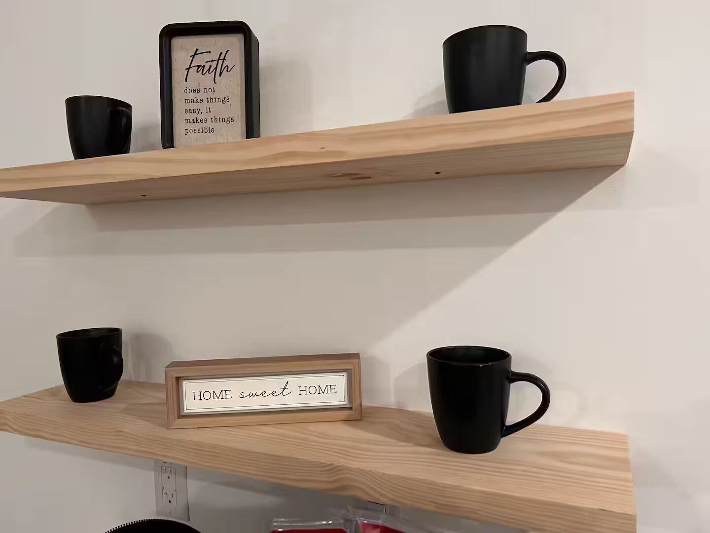 Dos estantes de madera con tazas negras y letreros motivacionales.