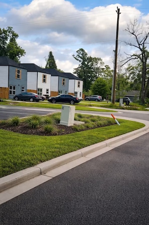 A residential street with houses, parked cars, and a grassy median. - Exotic Escapes | Modern Spacious 3BR Near Downtown (Houston)