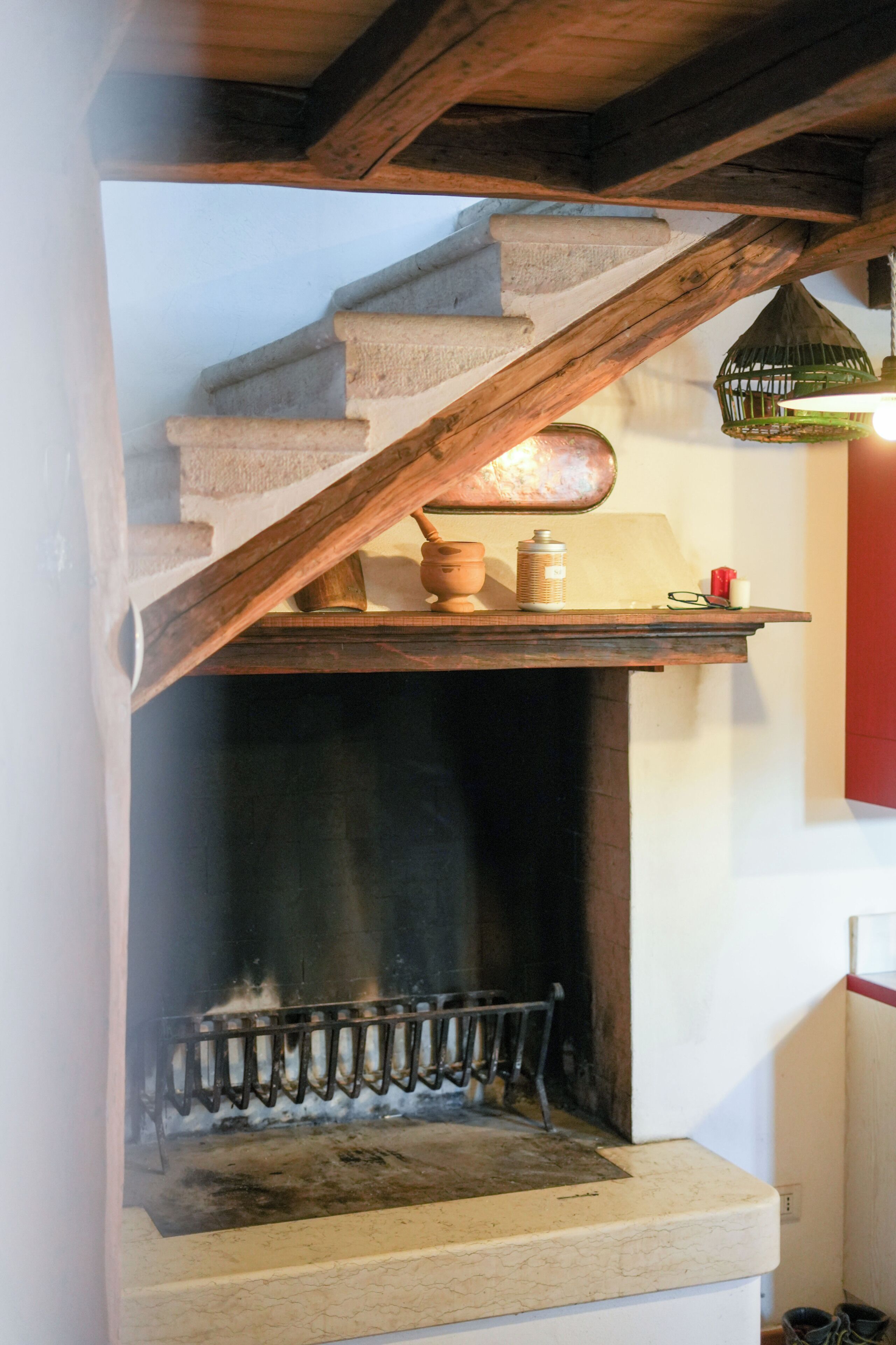 A staircase with a wooden handrail leading to a fireplace with a metal grate.