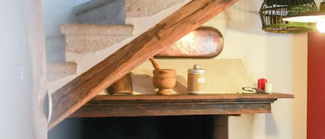 Una escalera con barandilla de madera que lleva a una chimenea con rejilla metálica.