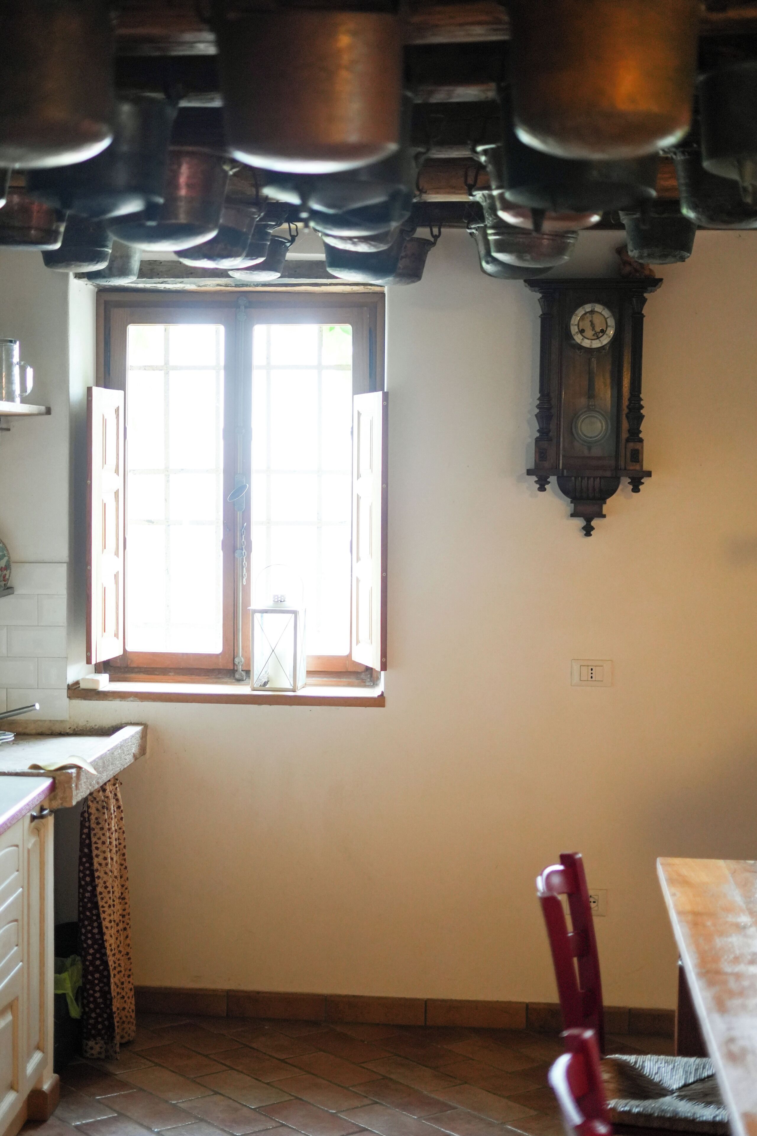 Une cuisine avec une fenêtre, une table en bois et une horloge fixée au mur.