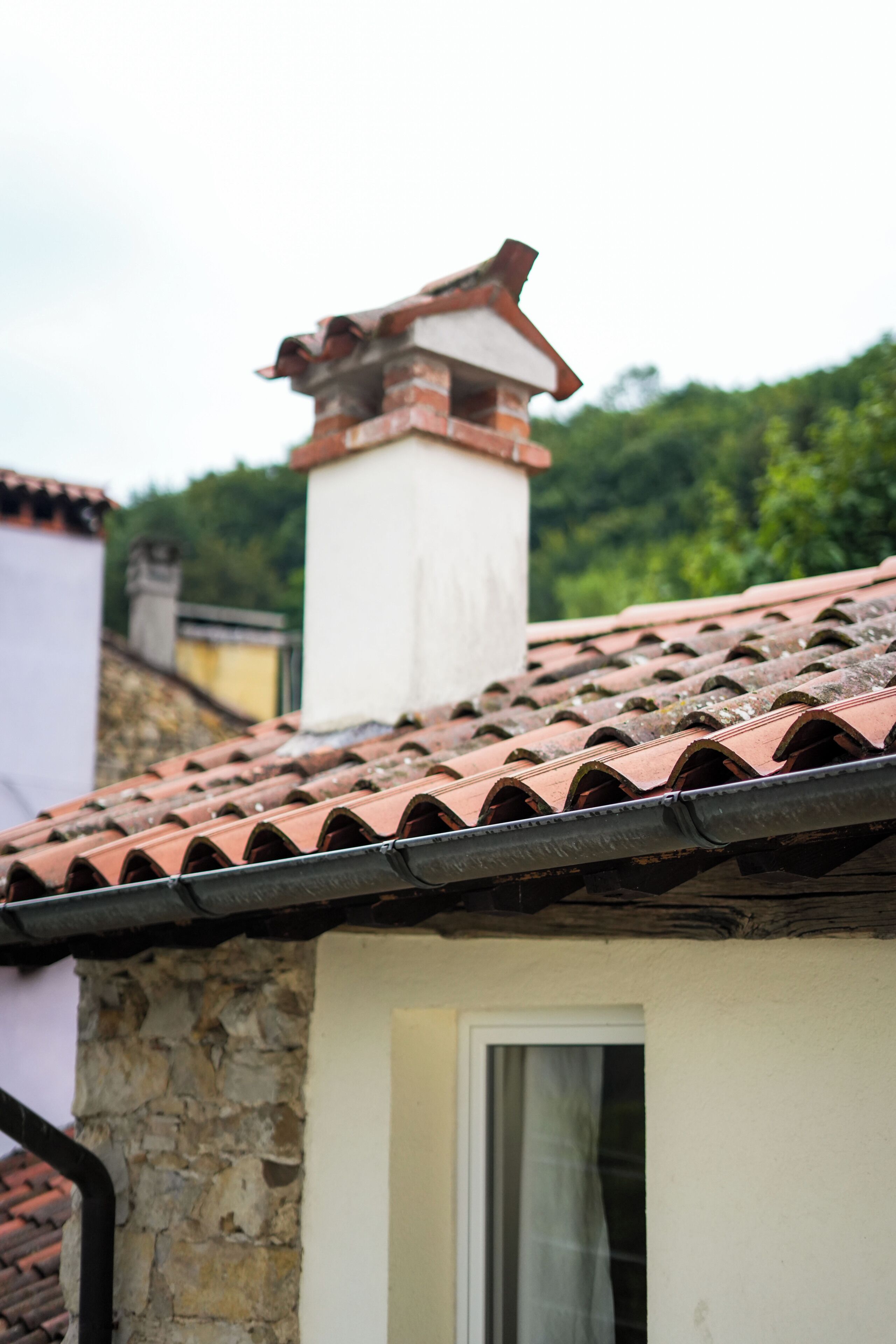 A stone building with a tiled roof and a chimney.